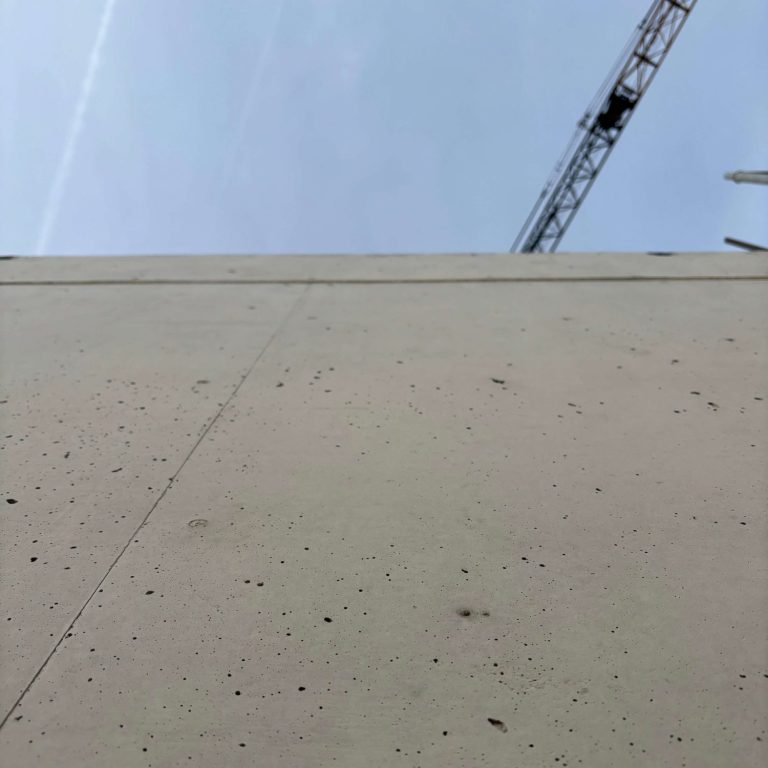 Qualitätssicherung am Bau Betongwand mit Blick nach oben, darüber ein Kran, blauer Himmel während Baubegleitung Raum Aschaffenburg